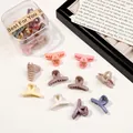 Close-up of colorful matte mini hair claws in a clear storage box with gift label - Cross / Milk Coffee