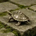 Close-up of a solid brass turtle figurine with detailed shell on a mossy stone - Lucky Turtle