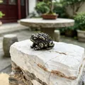 Detailed close-up of a solid brass Zen frog figurine on a natural stone for tea trays - Small Toad