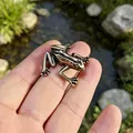 Miniature vintage bronze frog figurine shown on a hand for scale in a garden - Tree Frog