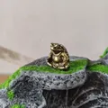 Close-up of a solid brass meditating frog figurine on a mossy stone desktop base - Meditating Toad