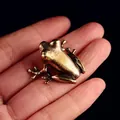 Macro shot of a solid brass Zen frog figurine being held in hand to show the mini size - Arrow Frog