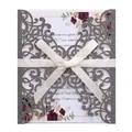 Close-up of laser-cut silver glitter invitation with a white silk ribbon bow - Gray