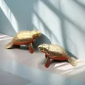 Detail of vintage brass manatee figurines with golden finish and artistic shadows - Manatee Shape