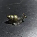 Macro shot of detailed copper snail figurine with antique finish on dark stone - Snail C