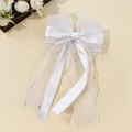 Detail of multi-layer white organza hair bow clip with silky ribbon on cream background - White