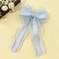 Detail of light blue layered organza bow hair clip with elegant long ribbons on silk fabric - Blue