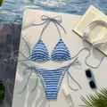 Dettaglio del bikini a righe bianche e blu con laccetti laterali e sfondo piscina - Blu