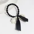Elegant black ribbon bow hair scrunchie with white pearl accents on white background - Pearl Bow Scrunchie / Black