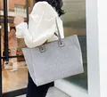 Sparkling grey large tote bag with metal chain strap worn by a model in outdoor setting - Gray