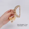 Pince à cheveux papillon dorée avec pendentif gland en cœur tenue à la main - Chaîne Demi-cercle Papillon Or