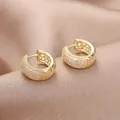Macro view of gold hoop earrings with pavé set white zircon on champagne silk background - Gold