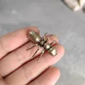 Detailed close-up of a realistic vintage brass ant figurine held in hand for scale - Army Ant