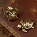 Set of two vintage brass turtle figurines with heart shells on an antique leather surface - Turtle