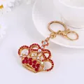 Close-up of golden crown keychain with red rhinestones and polished lobster clasp - Red