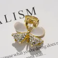 Eleganter goldener Schleifen-Haarclip mit weißen Opalsteinen und klaren Kristallen - Katzenaugen-Schleife