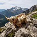 Statuina artistica di mucca delle Highland in metallo dorato su una roccia montana - Mucca delle Highlands