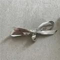 Detail of silver metallic bow hair clip with heart pendant on stone surface - Bowknot Heart Style (E4.3/J86-B52) / Silver