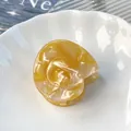 Elegant conch-shaped acetate hair claw clip with amber texture and gold spiral accents - Streaming Yellow