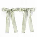 Detail of sage green satin bow hair clips with long ribbons and silky texture finish - Light Matcha Green