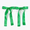 Close-up of bright green satin ribbon hair bows with long streamers and silk texture - Christmas Green