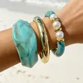 Gros plan d'un ensemble de bracelets en résine bohème avec perles sur fond de plage - Style de Patchwork de Perles Bleu Cyan (32807-bra-blue)