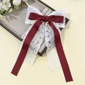 Gros plan sur le ruban en satin rouge et la dentelle florale blanche de la barrette - Bordeaux