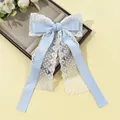 Détail du ruban en satin bleu clair et dentelle fleurie blanche sur la barrette - Bleu