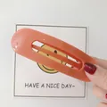 Grande fermaglio per capelli ovale arancione corallo opaco tenuto in mano - Fermagli per capelli a becco d'anatra / Arancione