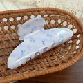 Pince à cheveux lilas avec motif floral bleu placée dans un panier tressé marron - Style Arche Fleuri Bleu Clair