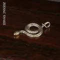 Detailed macro view of vintage brass snake pendant with intricate scales on wood background - Zodiac Snake