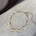Vista detallada del collar de perlas doradas onduladas sobre fondo de tela denim - Pulsera de perlas onduladas con enrejado de uvas / Dorado