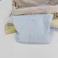 Detail der blau gestreiften Kosmetiktasche mit feiner Schleifenstickerei und Baumwolltextur - Blau Weiß Gestreift Blauer Bogen