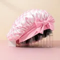 Detailed texture of pink and white checkered satin sleep cap with a large decorative bow - Pink Plaid