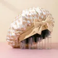 Close-up of satin hair bonnet featuring beige checkered pattern and large decorative bow - Khaki Plaid