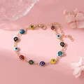 Schickes mehrfarbiges Evil Eye Perlenarmband mit verstellbarer Goldkette auf rosa Hintergrund - Mehrfarbig / Gold