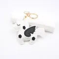 Detail shot of a handmade leather unicorn keychain with black wings and gold metal ring - White Unicorn Pegasus