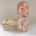 Handmade crochet pink carnation with Mother's Day tag on minimal warm book background - Pink Carnation
