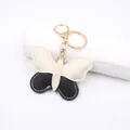 Close-up of butterfly leather keychain with black and cream contrast stitching - Beige-Black