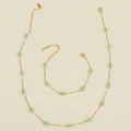 Detailed close-up of golden stainless steel chain with mint green beaded flower charm - Grape Green Necklace And Bracelet