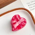 Pince à cheveux en forme de cœur en acétate marbré rose présentée sur un plat - Rose Baie