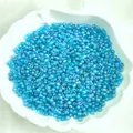 Ice blue translucent glass seed beads in a shell dish for DIY jewelry making - Iridescent Blue 163