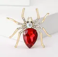 Close-up of spider brooch with large red teardrop gemstone and white rhinestones - Gold and Red Spider Style