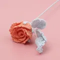 Handmade crochet rose in peach pink with light blue leaves on a soft pink backdrop - Macaron Roselle Rose - Orange (Blue Leaf)