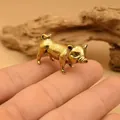 Detailed macro shot of a miniature brass pig figurine resting on a fingertip - Realistic Female Pig - Crouching Pose