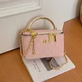 Rosa gesteppte Box-Tasche mit goldenem Metallgriff und floralem Logo-Detail - Rosa