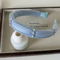 Light blue fabric headband with elegant white pearls and beads on a ceramic stand - Pearl Decorative Thin Headband / Blue
