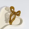 Olive green acetate butterfly hair claw clip displayed on an elegant wavy tray - Bow Ginger Yellow