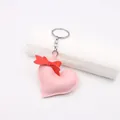 Close-up of pink leather heart charm with red ribbon bow and silver metal keychain - Pink