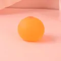 Close-up of breast-shaped stress relief toy made of soft silicone in peach color - 4cm / Orange